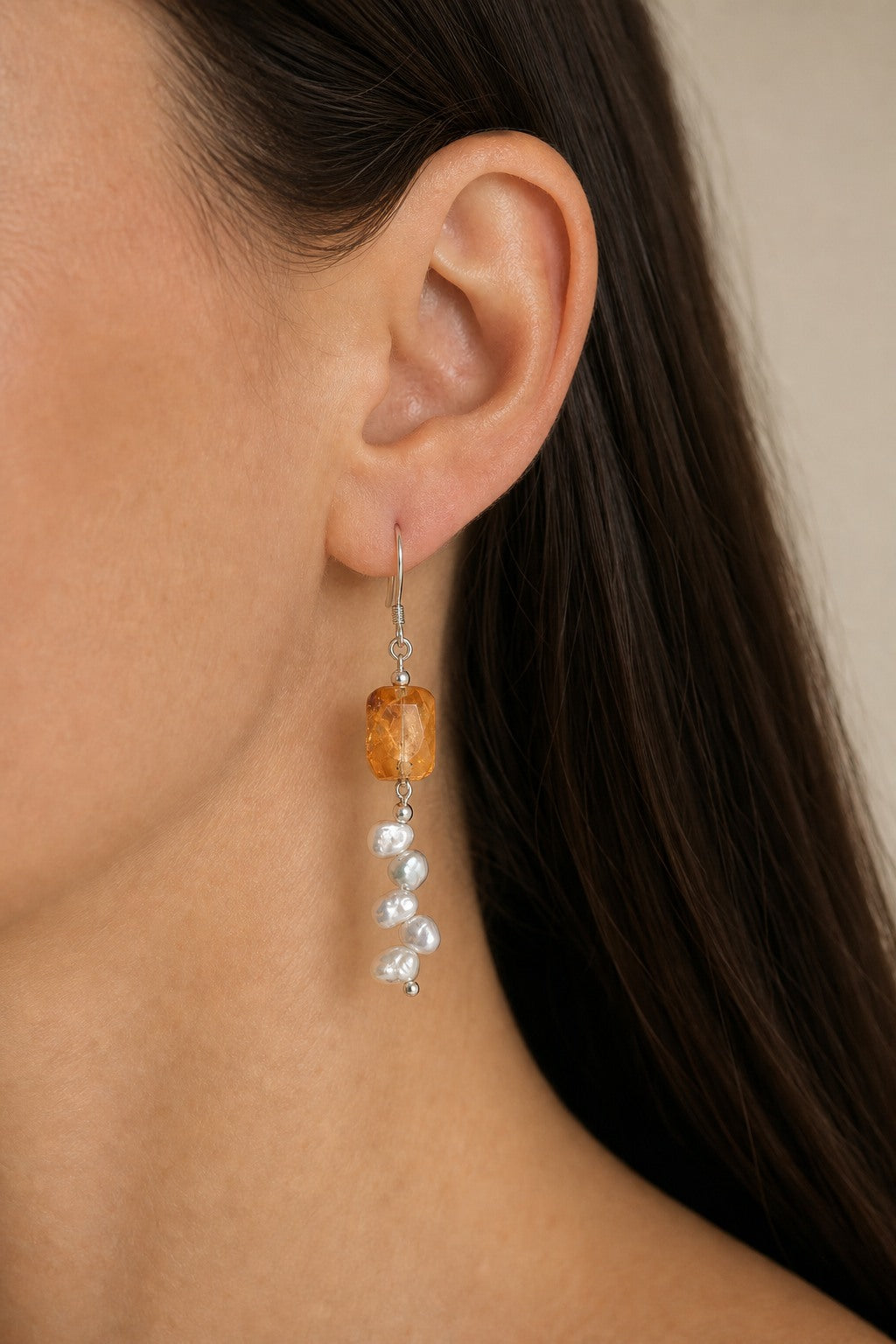 Citrine and baroque pearl earrings worn on an ear at realistic scale