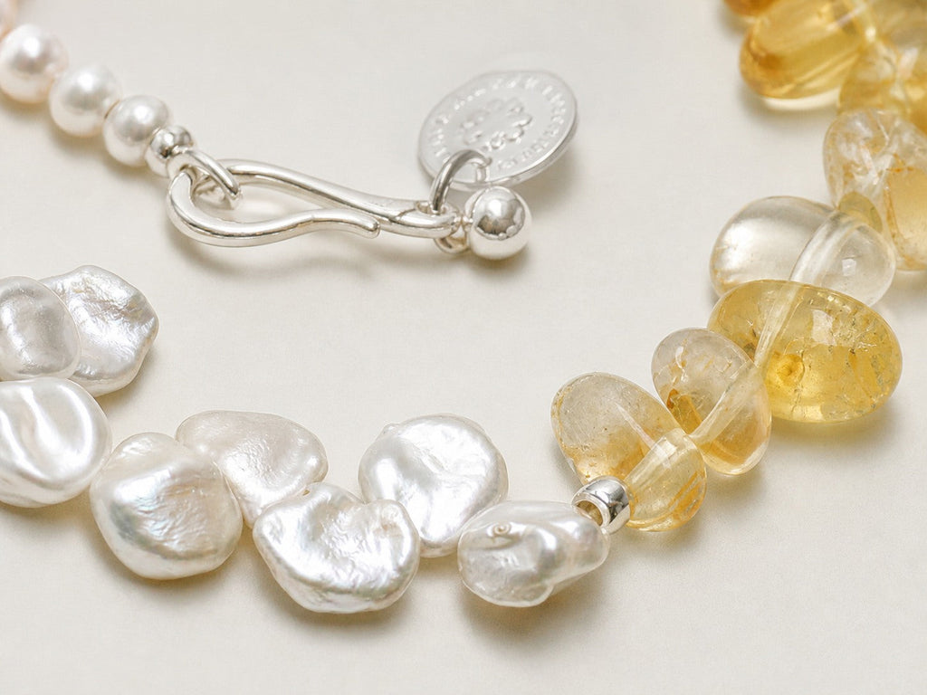 Close-up of citrine, freshwater pearls, sterling silver S-hook and charm workmanship