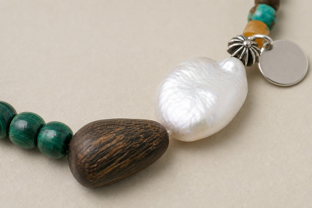 Close-up of malachite, agarwood, baroque pearl and sterling silver bracelet workmanship