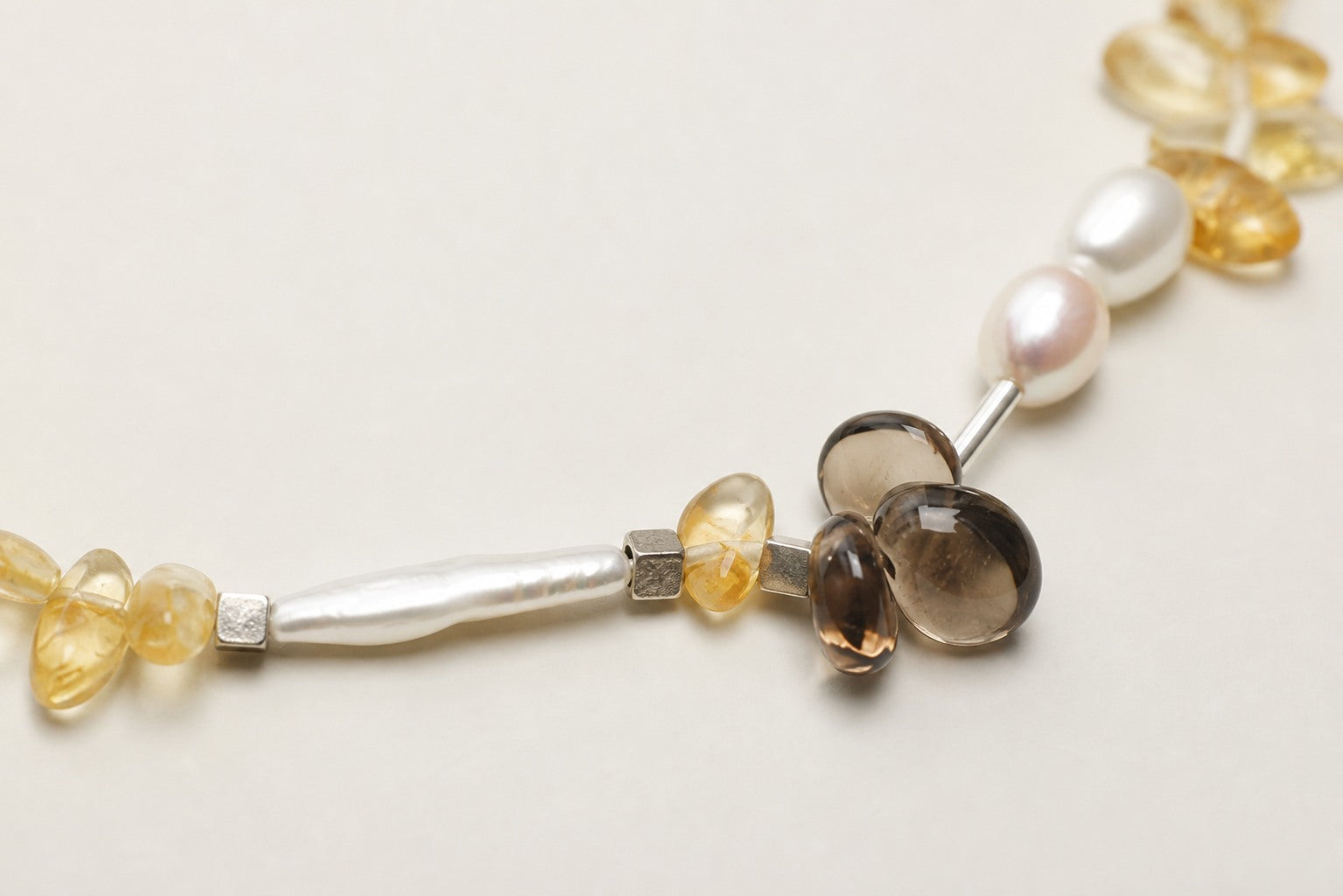 Close-up of citrine, smoky quartz, freshwater pearls and sterling silver necklace workmanship