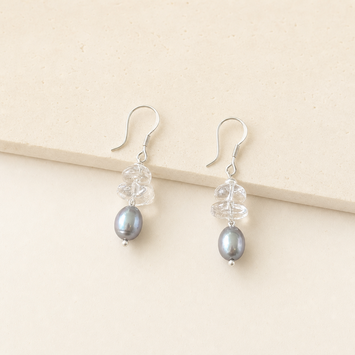 Crystal grey pearl drop earrings with clear crystal chips on an ivory studio background
