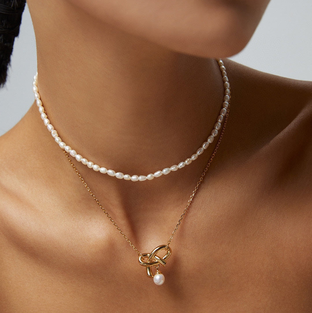 Rice pearl necklace worn with a separate gold-tone pendant necklace