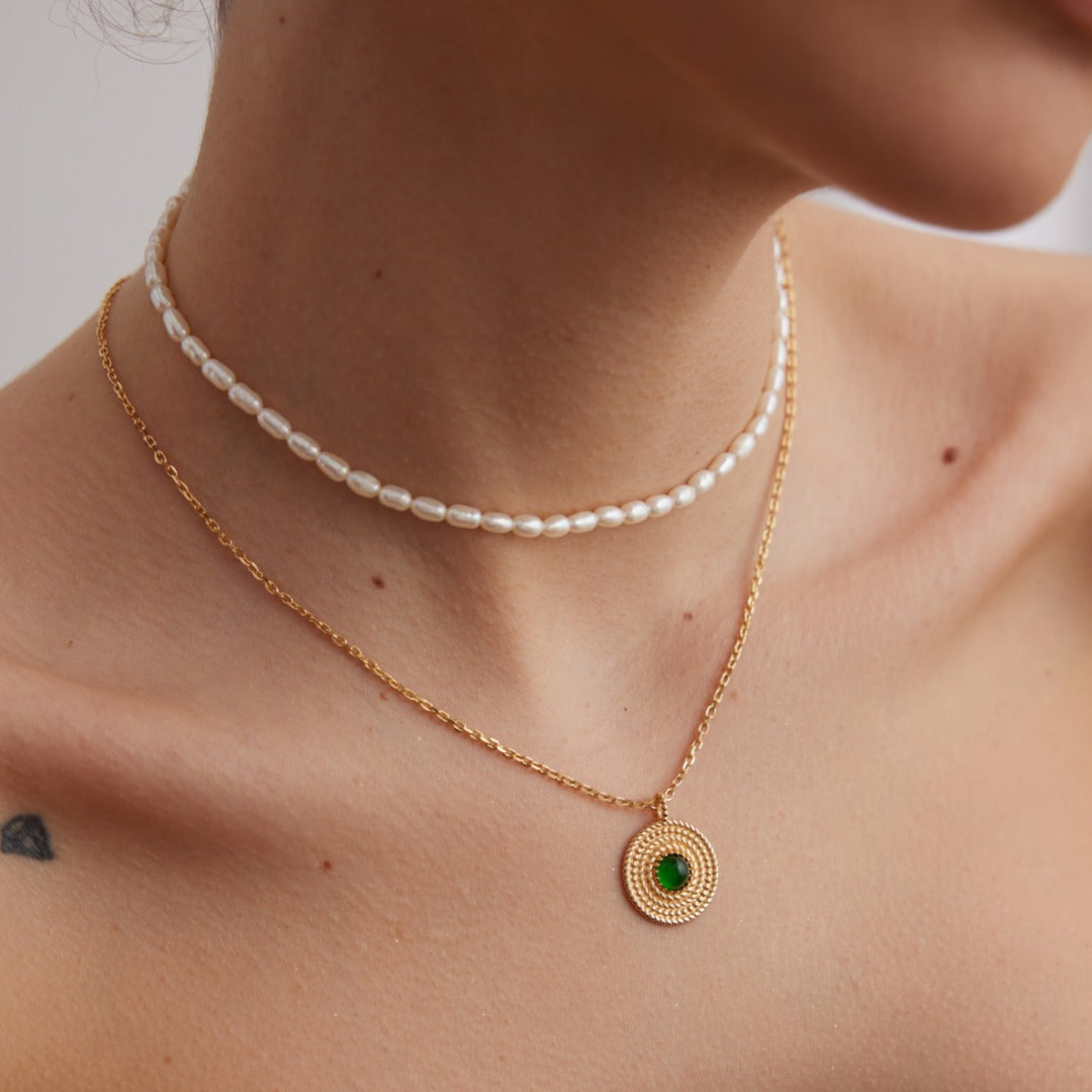 Close-up styling photograph of a pearl strand and a separate pendant necklace