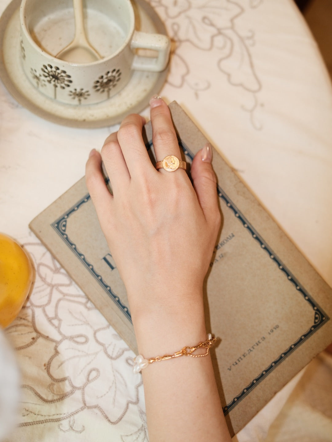 Portrait medallion ring worn on a hand beside an open book