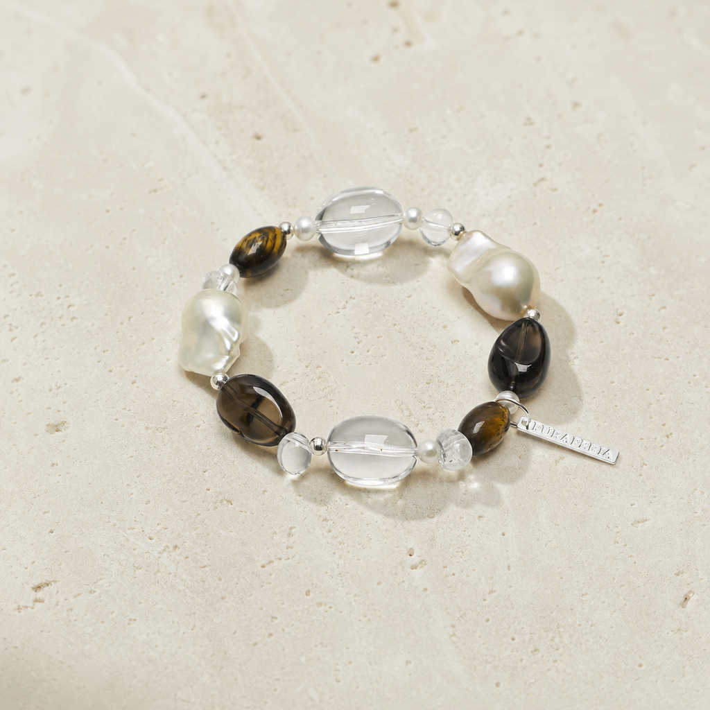 Smoky tiger eye pearl bracelet on a warm ivory studio background