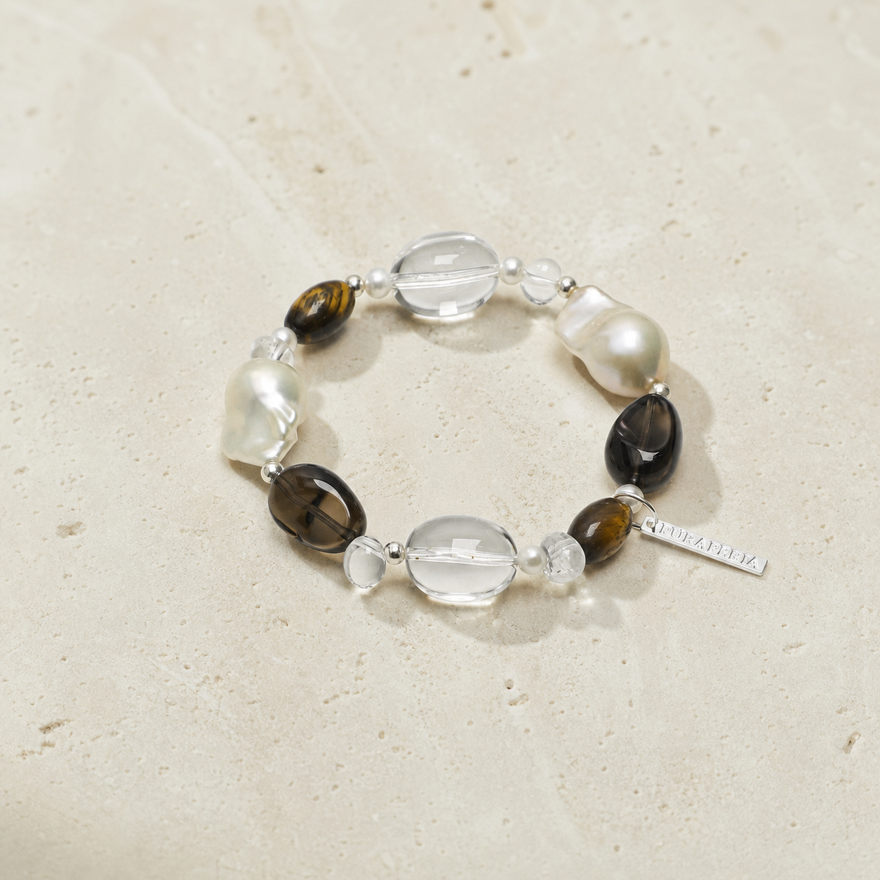 Smoky tiger eye pearl bracelet on a warm ivory studio background