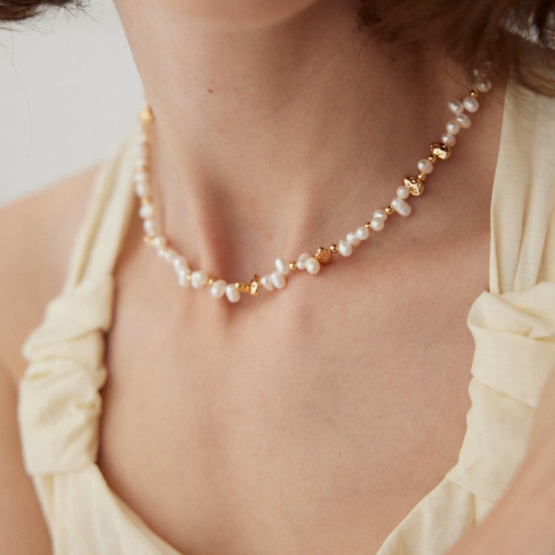 Pearl and gold-tone bead necklace at the neckline